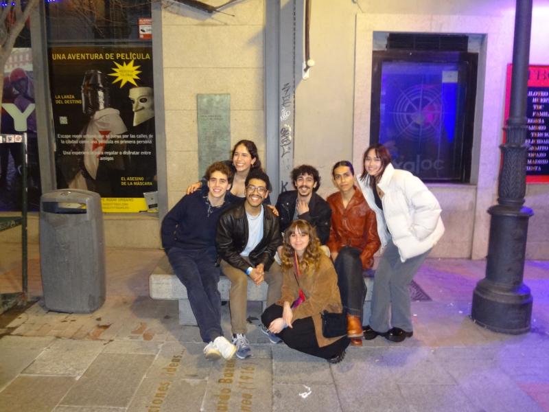 Jose with 6 friends seating on a bench at Madrid during the night.