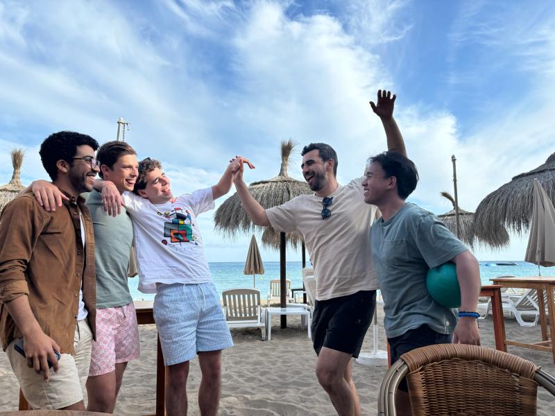 Group of 5 friends standing in front of the beach at Ibiza, Spain.