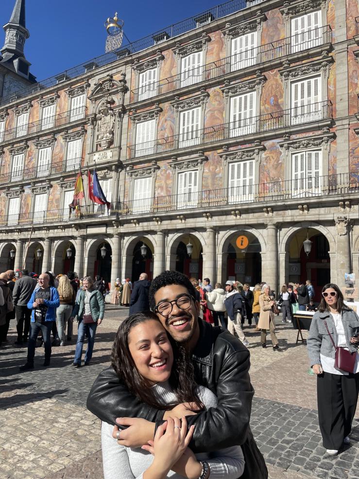 Jose hugging her friend Maria in front of the old buildings of Plaza Mayor, Madrid.