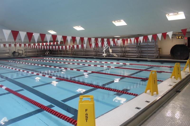 Indoor swimming pool with lane markers and red-and-white flag overhead.