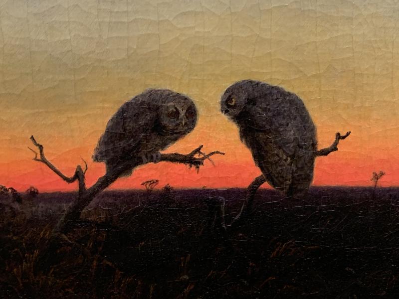 Picture of a painting of two owls standing on branches in an empty field at sunset.