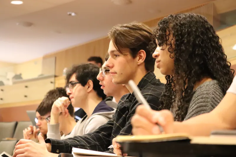 Students attentively listening in a lecture hall.