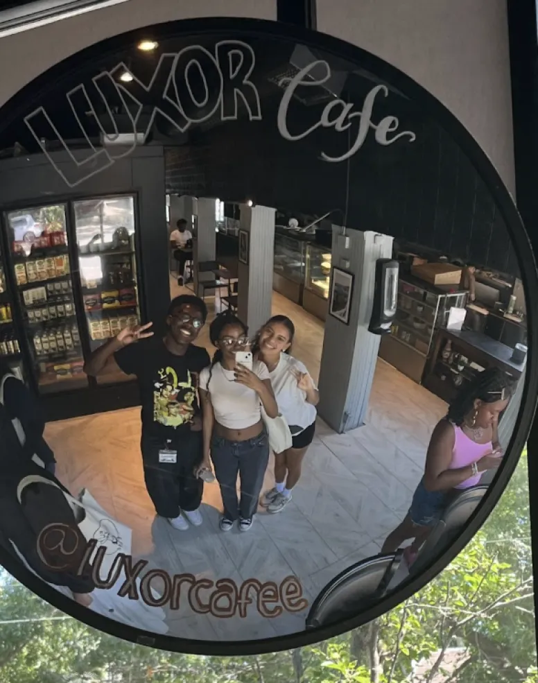 Three students taking a mirror selfie in a cafe near Harvard's campus.