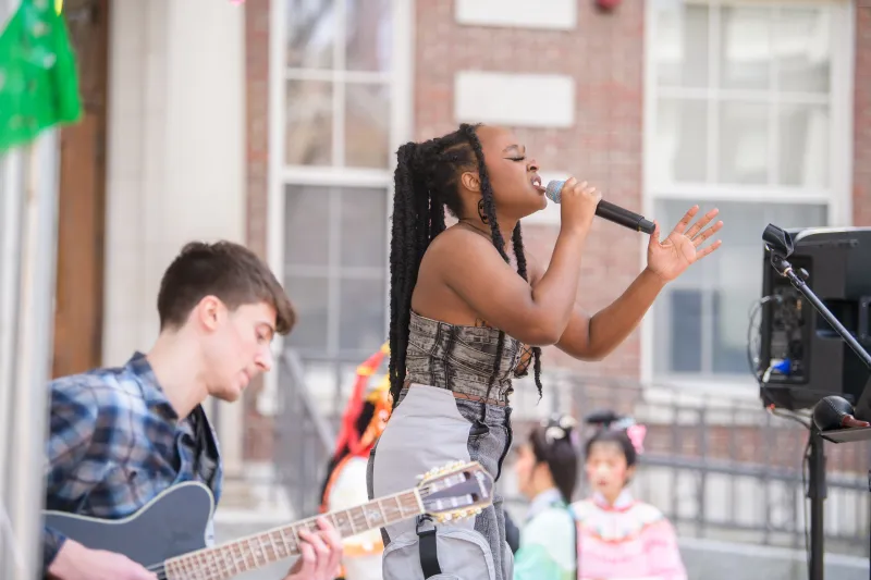 Singer performing with a guitarist at an outdoor event.