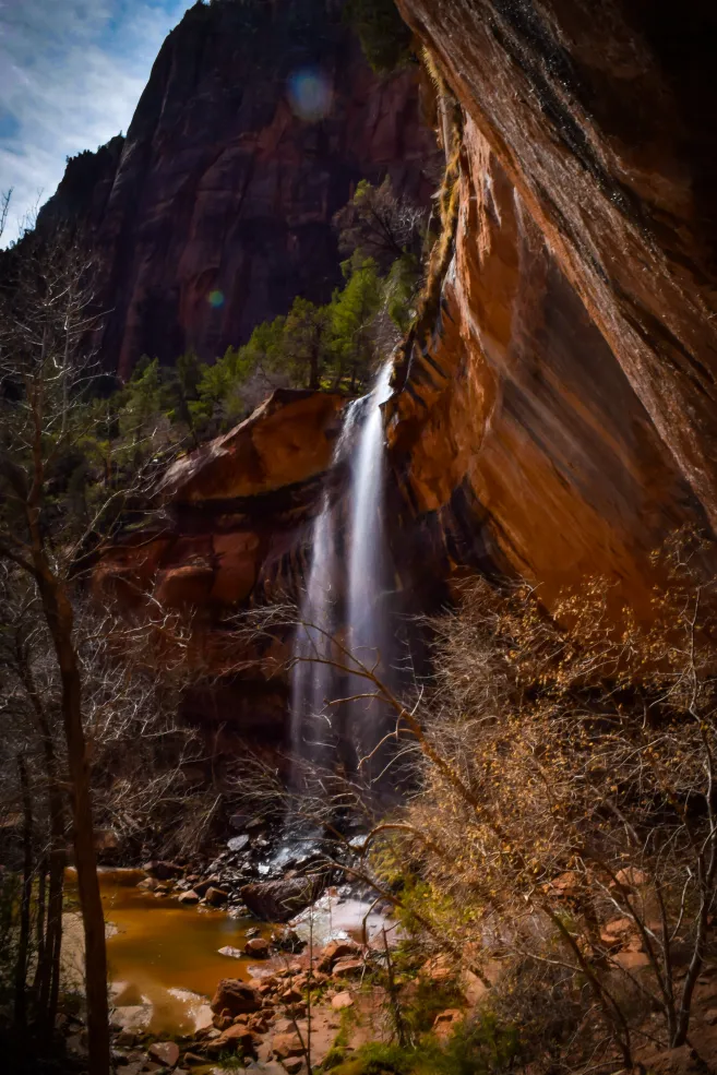 A picture of a waterfall at Emerald Pools over red rocks.
