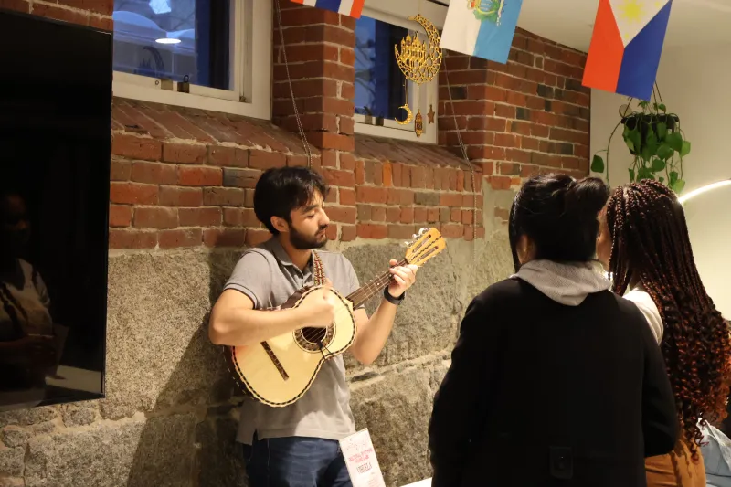 A picture of a student playing an instrument for two girls 