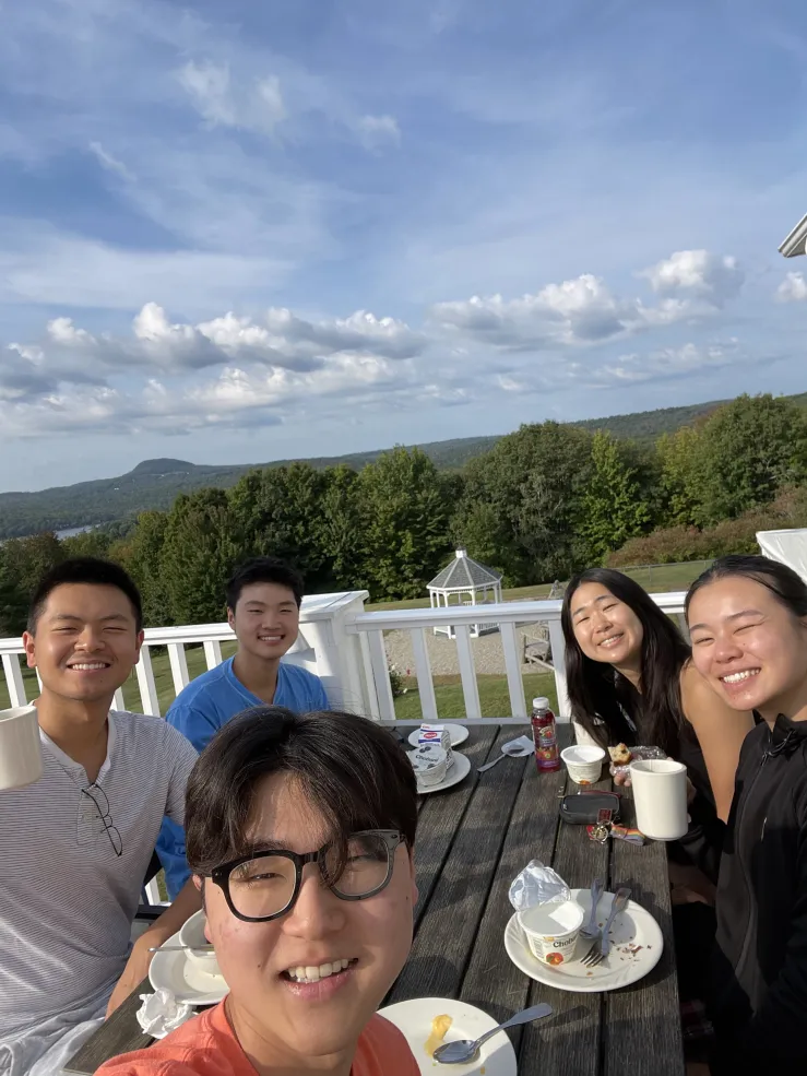 A group picture of Raymond and his friends in front of rolling hills and trees in Maine.
