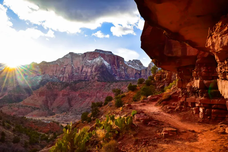 A picture of the Watchman Trail with the setting sun and snow-capped mountains in the background. 