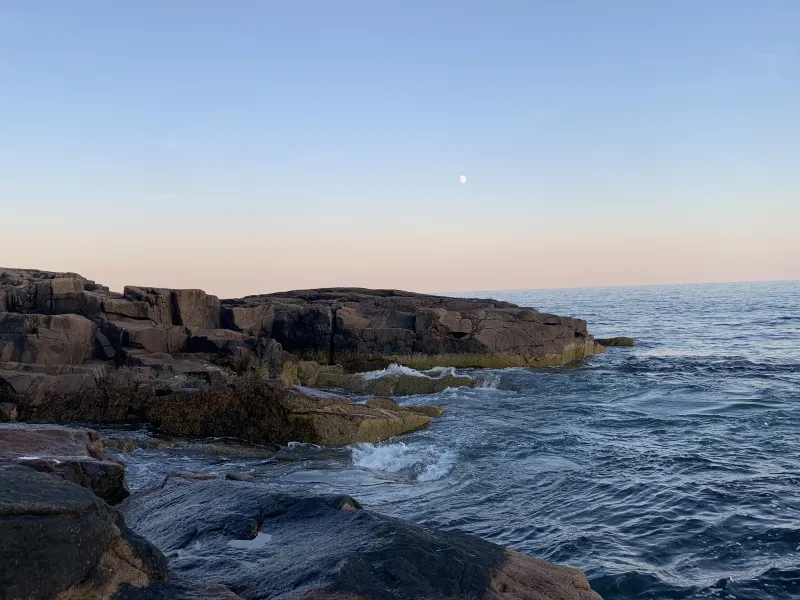 A picture of rocks jutting into the ocean water with waves crashing onto the shore.