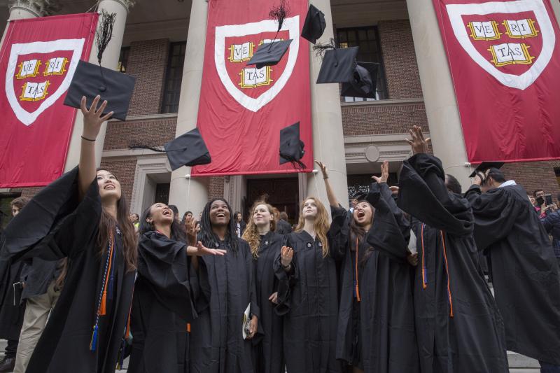 Graduates in gowns celebrate by tossing caps in the air