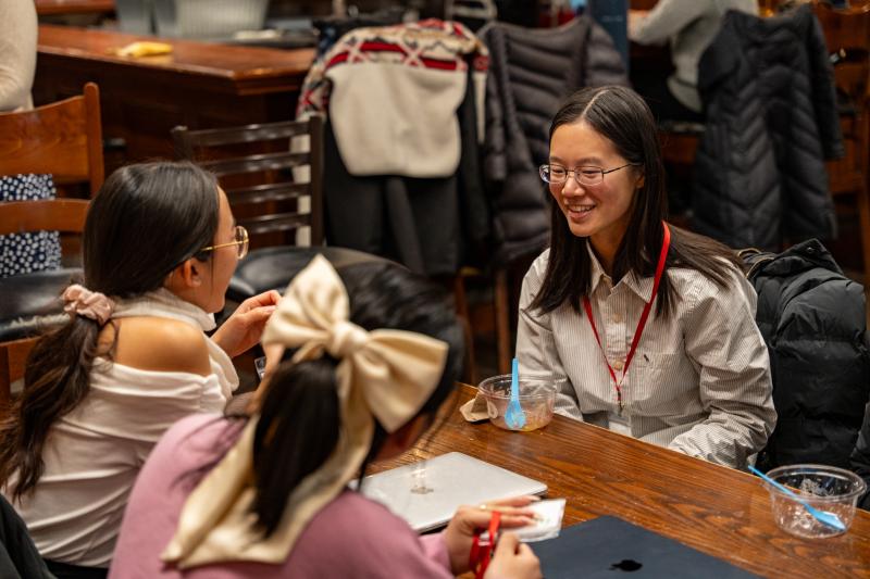 3 girls seated at a table talking in conversation.
