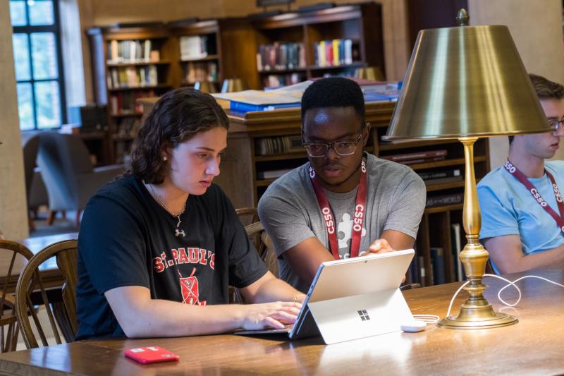 Inno (and a student) looking and pointing at a screen during CS50's Sunday office hours in the Widener Library's Loker Reading Room.