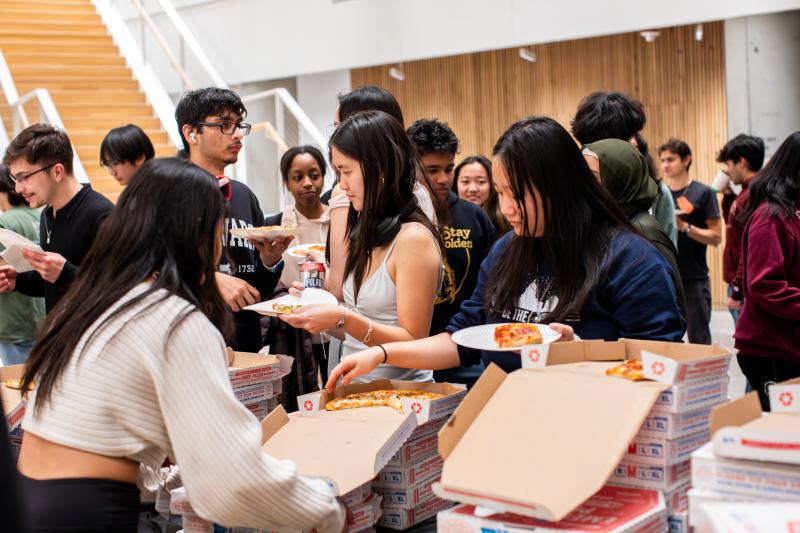 CS50 Hackathon (fall 2024) attendees grabbing pizza.