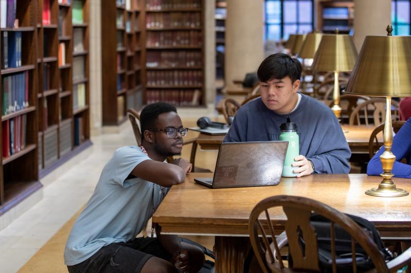 Inno and a student looking at a screen during CS50's Sunday office hours in the Widener Library's Loker Reading Room.