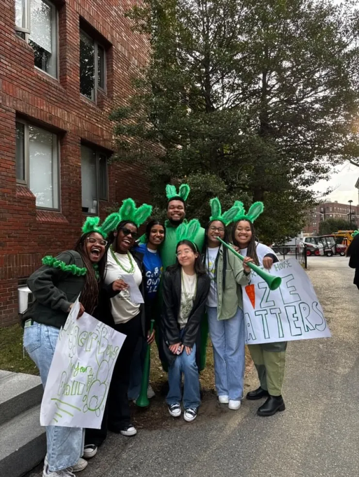 Group of students in front of Canaday Hall, a first year dorm. Most are wearing Leverett House merchandise, with one person wearing a Lowell House shirt.