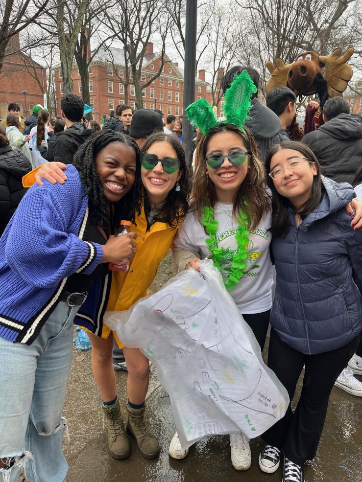 A group of four girls smiling and wearing Leverett House merchandise in Harvard Yard on Housing Day 2024.
