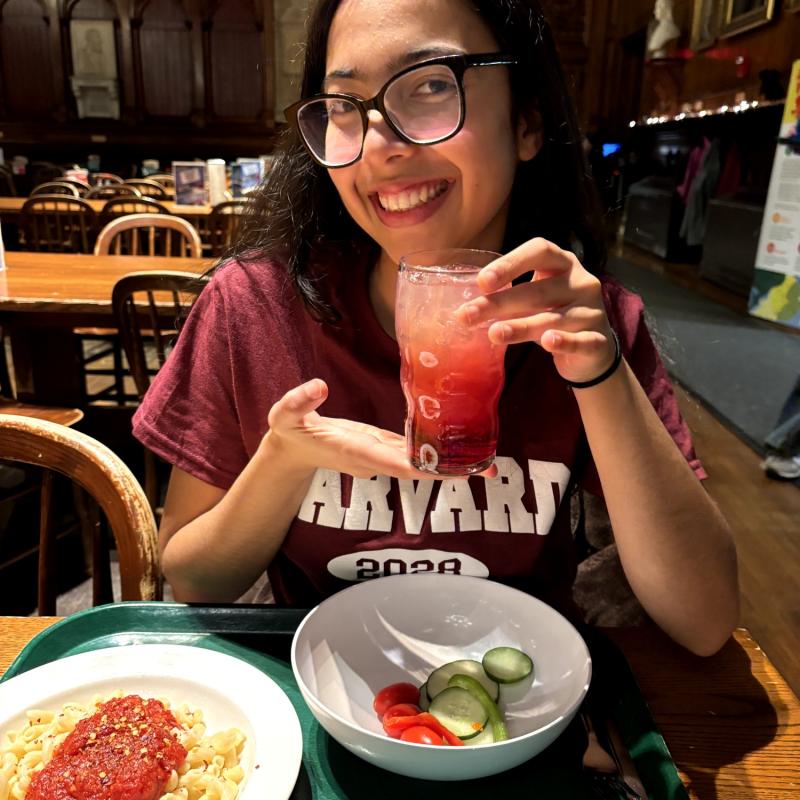 The author holding up her layered drink, Dreamer’s Fuel, at Annenberg, wearing a Harvard T-shirt.