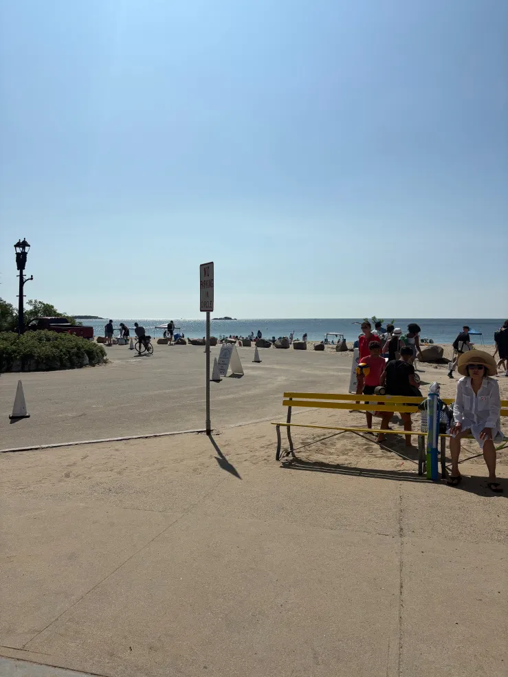A view of Singing Beach's front entrance. Water in the background and people walking around
