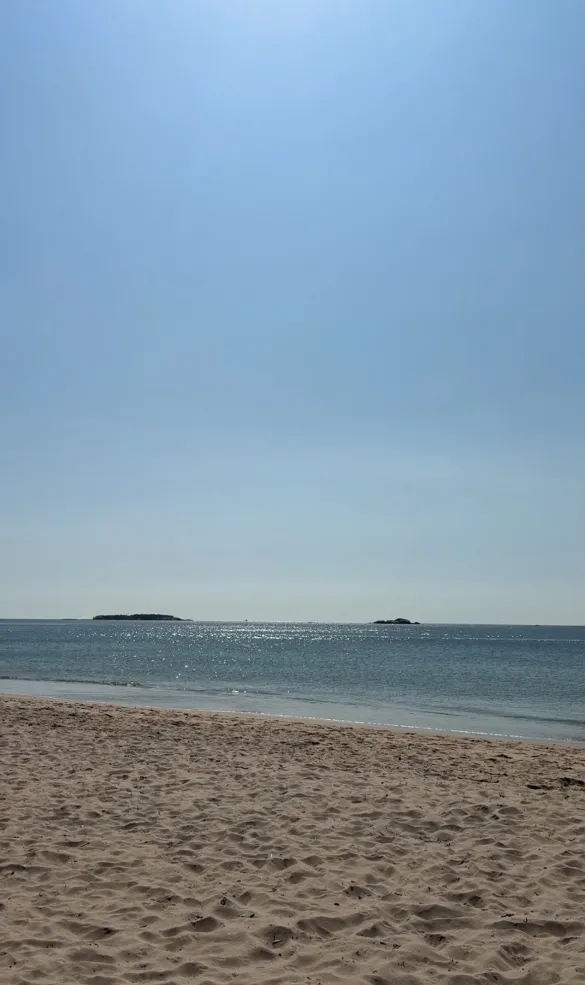 Empty beach, with sand and blue waters.
