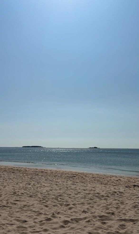 Empty beach, with sand and blue waters.