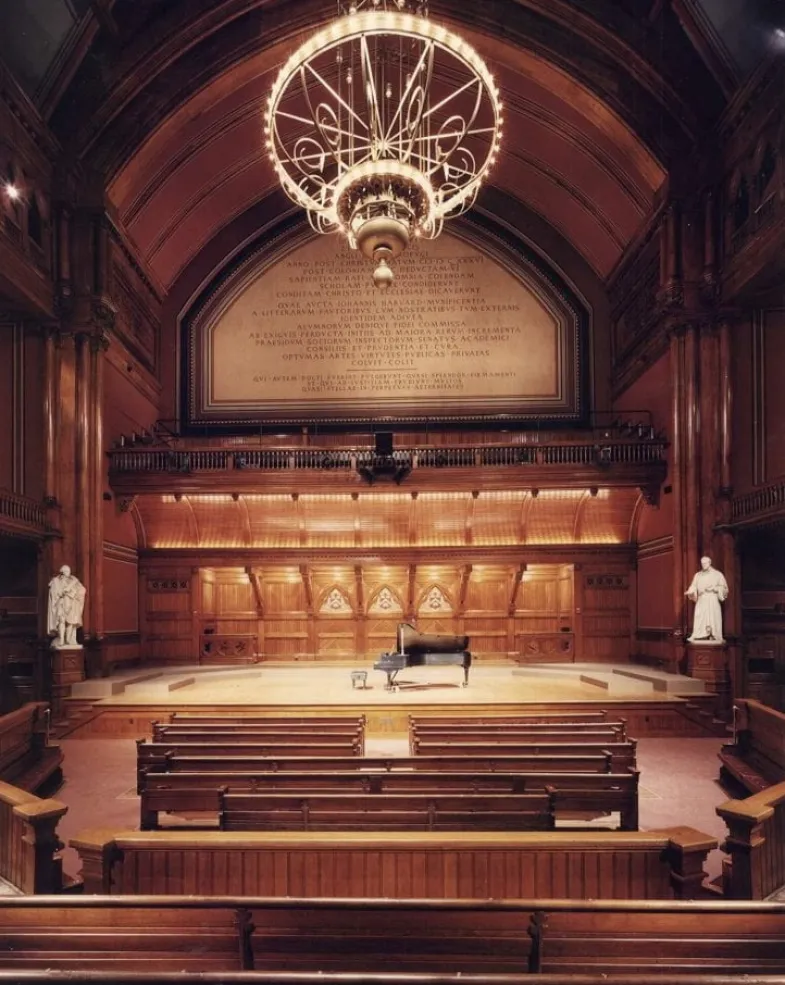 Empty Sanders Theatre with warm lighting, wooden interior, and intricate architectural details, highlighting the elegance of the historic performance space.