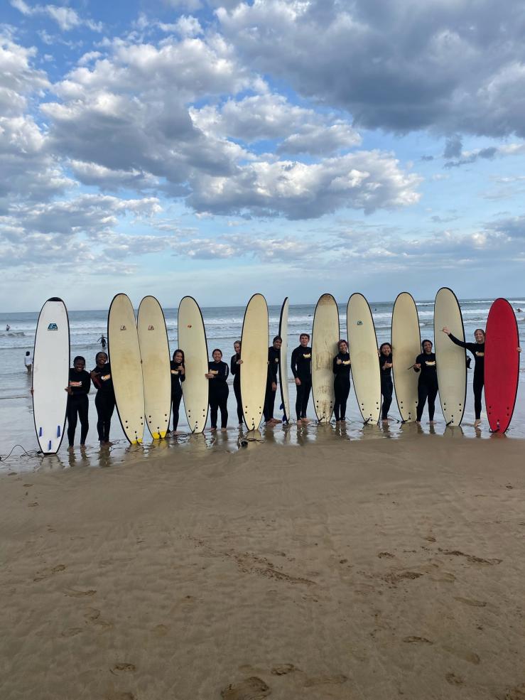 My study abroad program posing for a photo of us on the beach, holding our surf boards. 