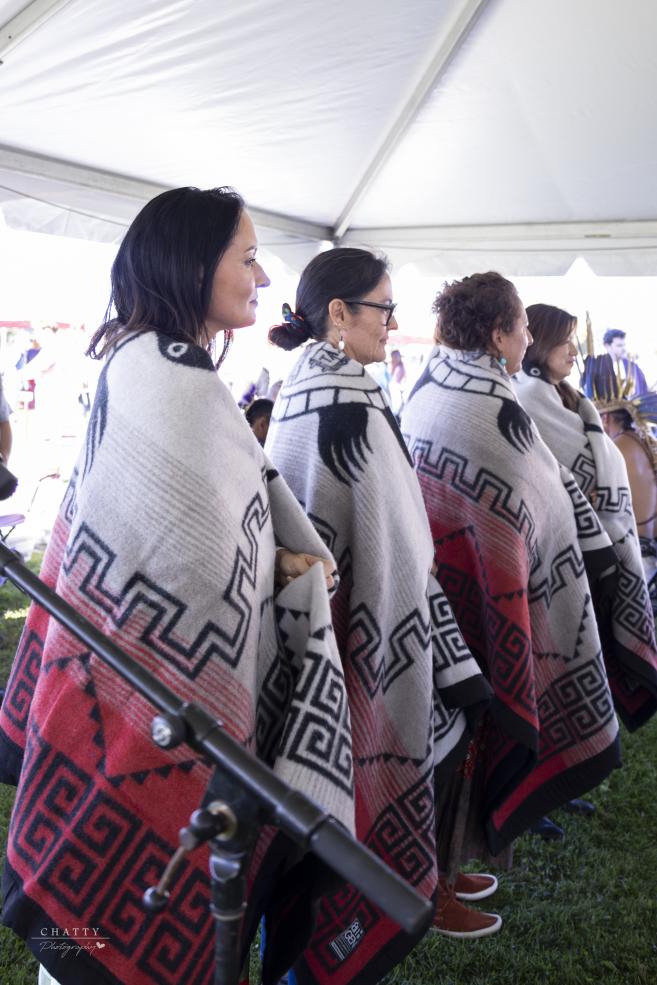 Four female honorees stand side by side as they are blanketed during the 2025 Harvard Powwow.