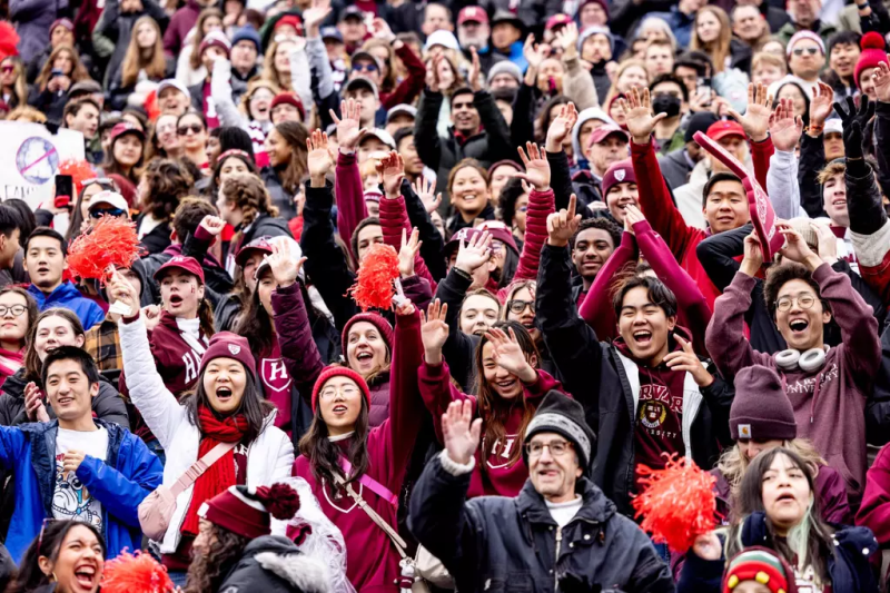 Crowd of students in maroon cheering at a sports event.
