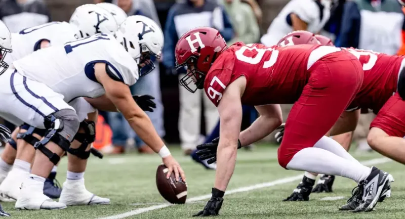 Harvard and Yale football players lined up at the line of scrimmage.