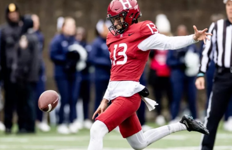 Harvard football player punts the ball during a game.