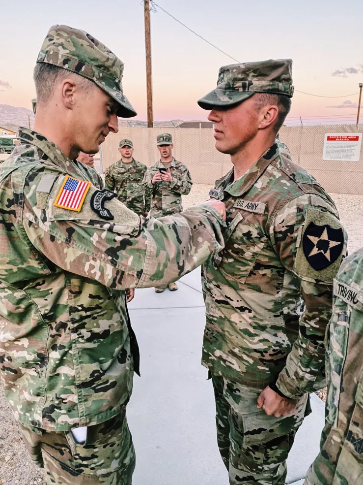 An enlisted soldier stands in front of an officer during a military promotion ceremony