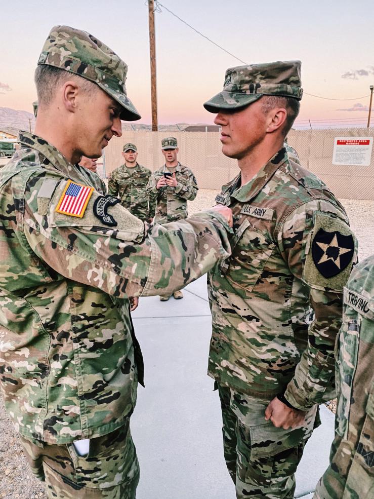 An enlisted soldier stands in front of an officer during a military promotion ceremony
