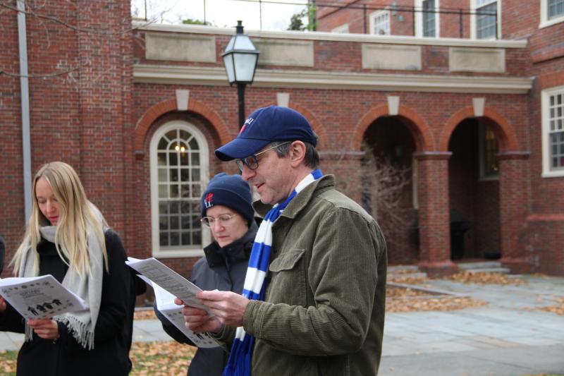 Professor David Laibson reads sheet music and joins the carolers in song.