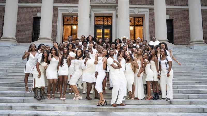 Group of students in white taking a photo at widener steps