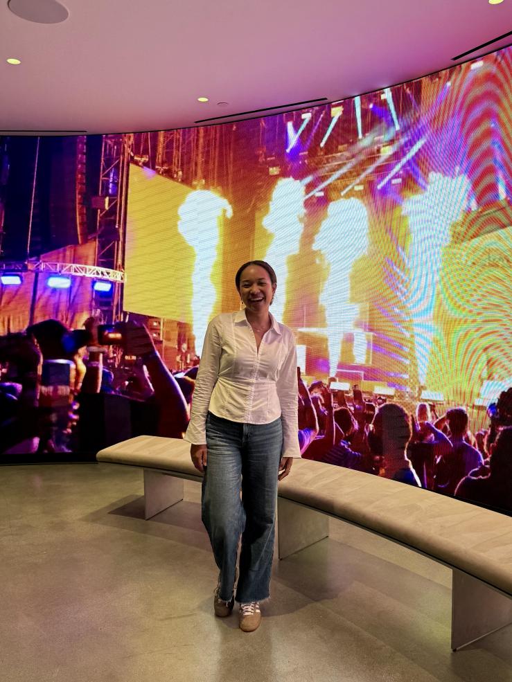 Student Renee Perpignan in front of a large screen playing a concert.