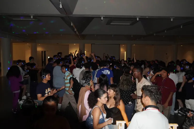 students at a silent disco, with lit up headphones