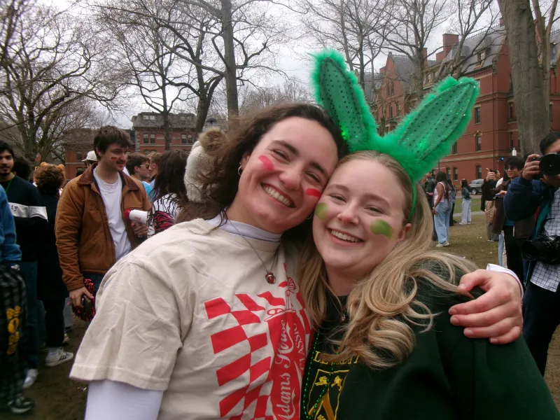 Two friends hugging and smiling at the camera on housing day. 