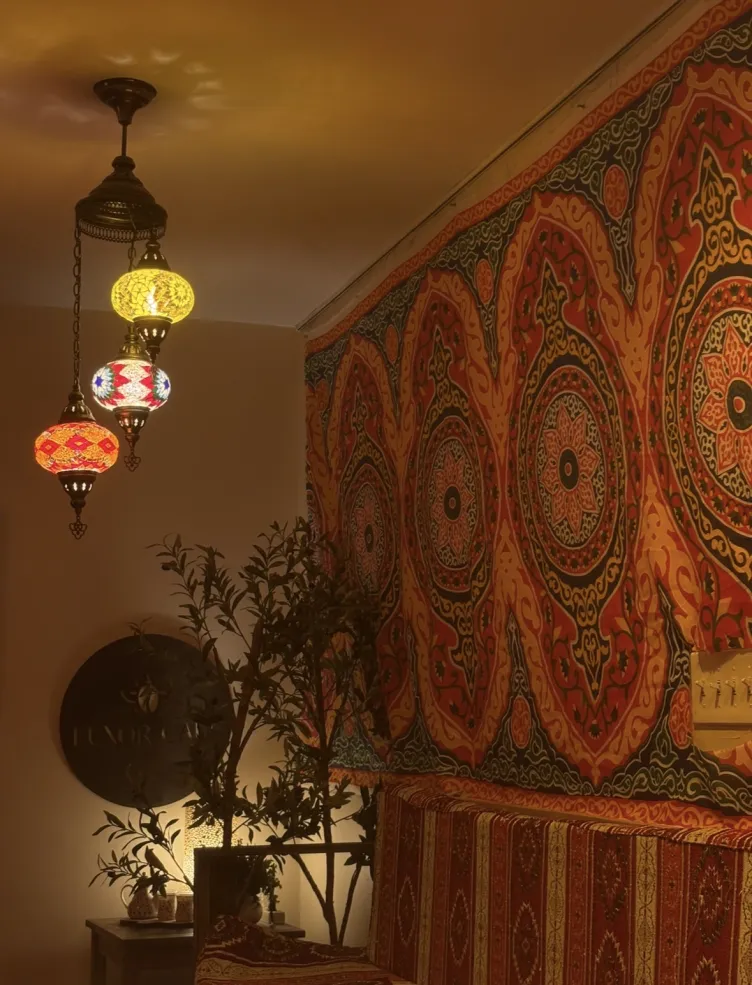 Dimly lit room with lanterns, plants, and a tapestry on the wall 