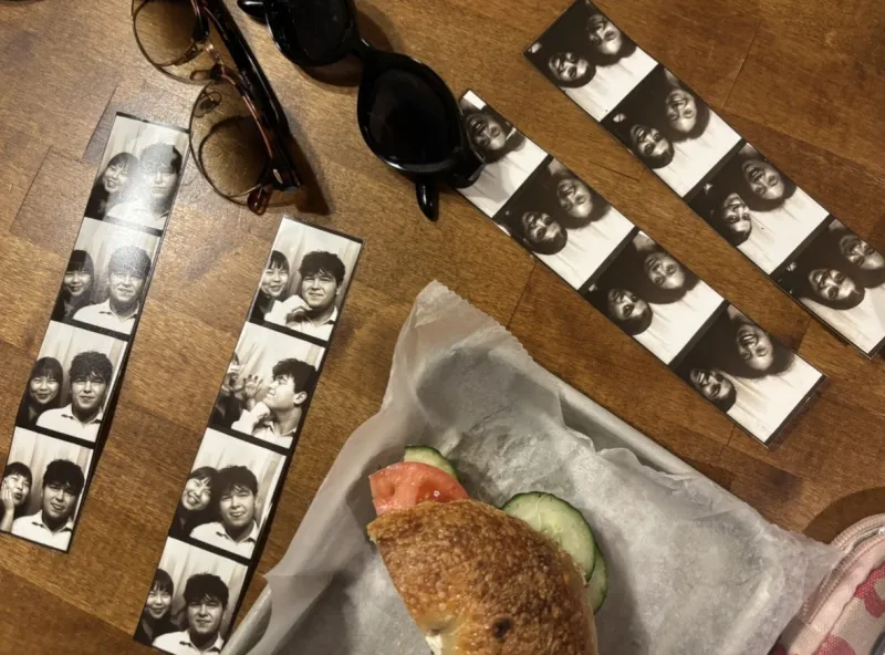 Table with 4 photobooth strips, a bagel, and sunglasses