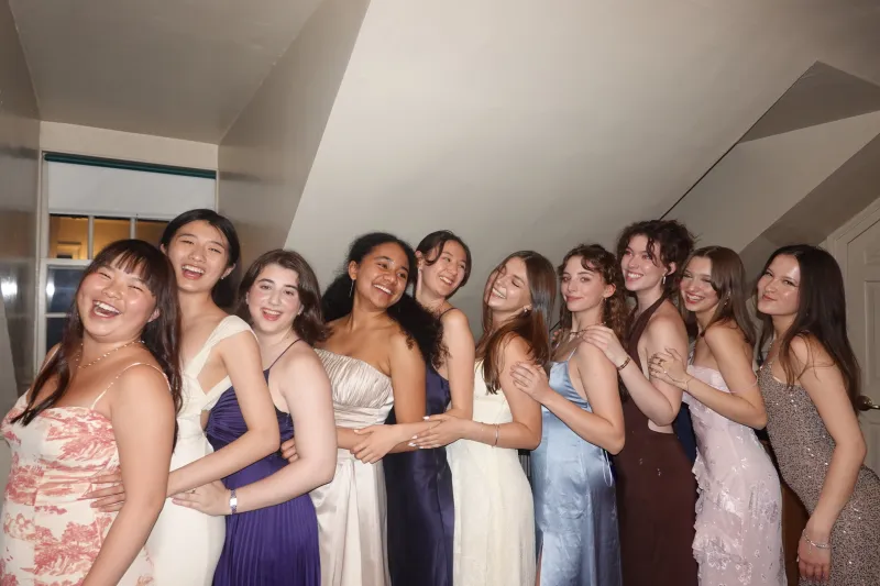 Group of ten girls in formal dresses, lined up and laughing 