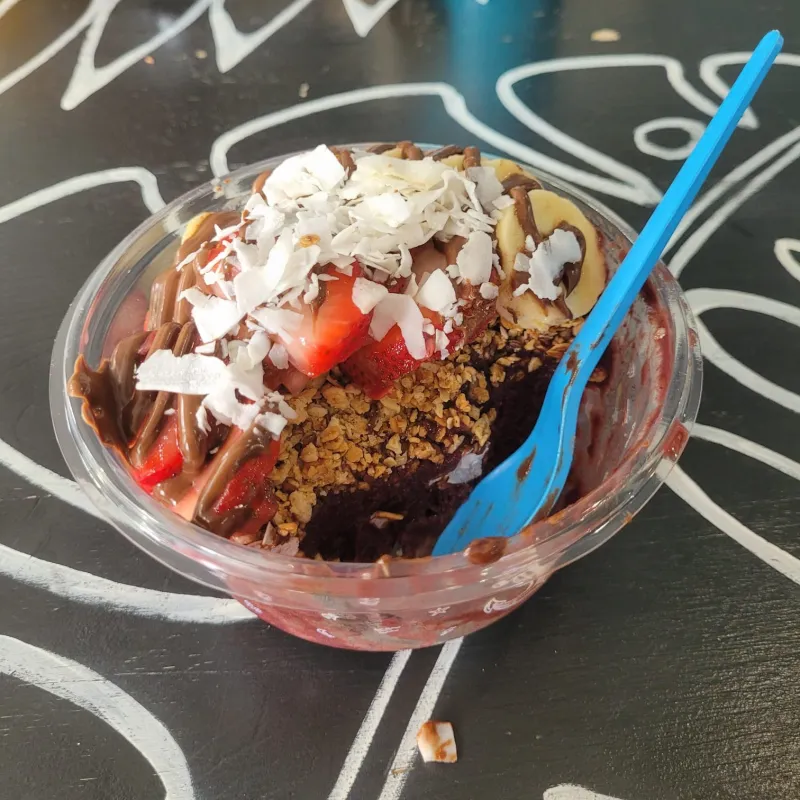 A acaí bowl with fruit toppings and a blue spoon