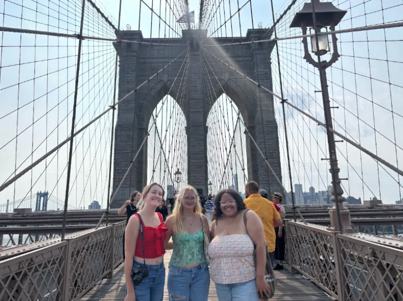 Three friends standing on the Brooklyn Bridge. 