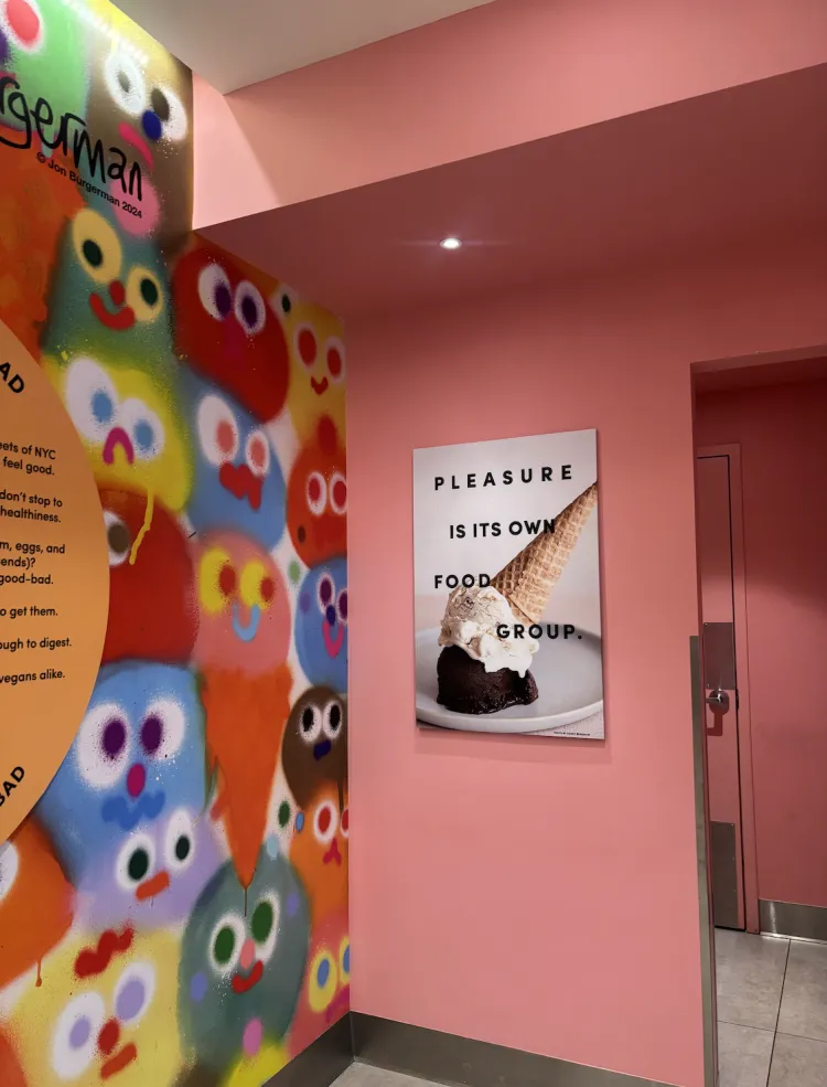 Art on the walls inside of Van Leeuwen featuring colorful faces and also a photo of an ice cream cone