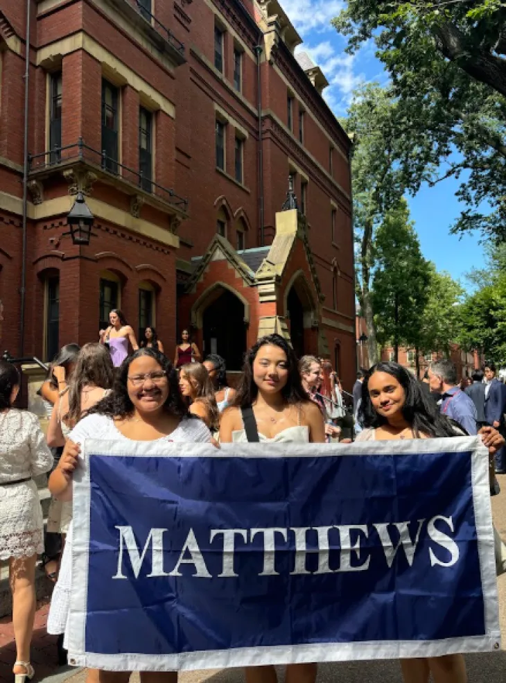 Three roommates holding their first-year dorm flag.