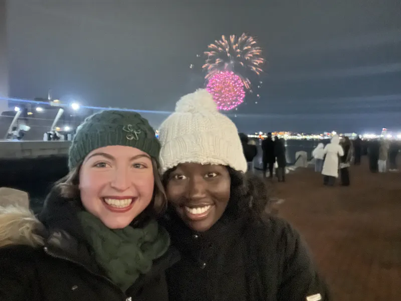 Elizabeth and Cristiana smile together at Boston's Seaport during the New Year's Eve fireworks, celebrating the close of another year and the friendship they've built at Harvard.