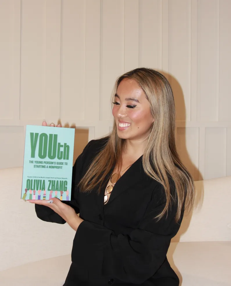 Olivia Zhang '27 holding up a copy of her book.