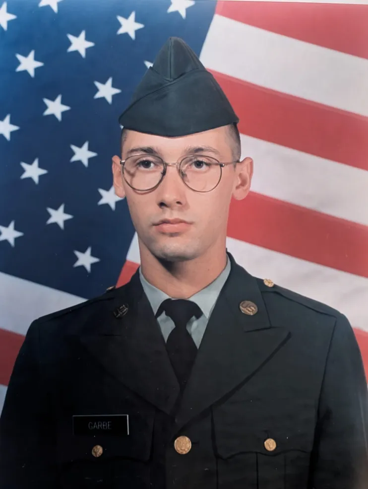 Cory Garbe '30 in his military uniform against a backdrop of the American flag.