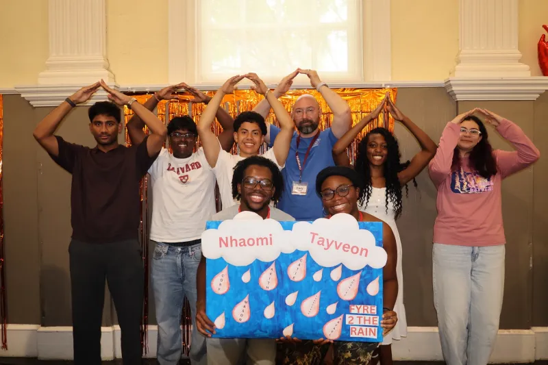 Carbe (center, wearing a blue shirt) making a house symbol with his hands next to other students who participated in the FYRE program.