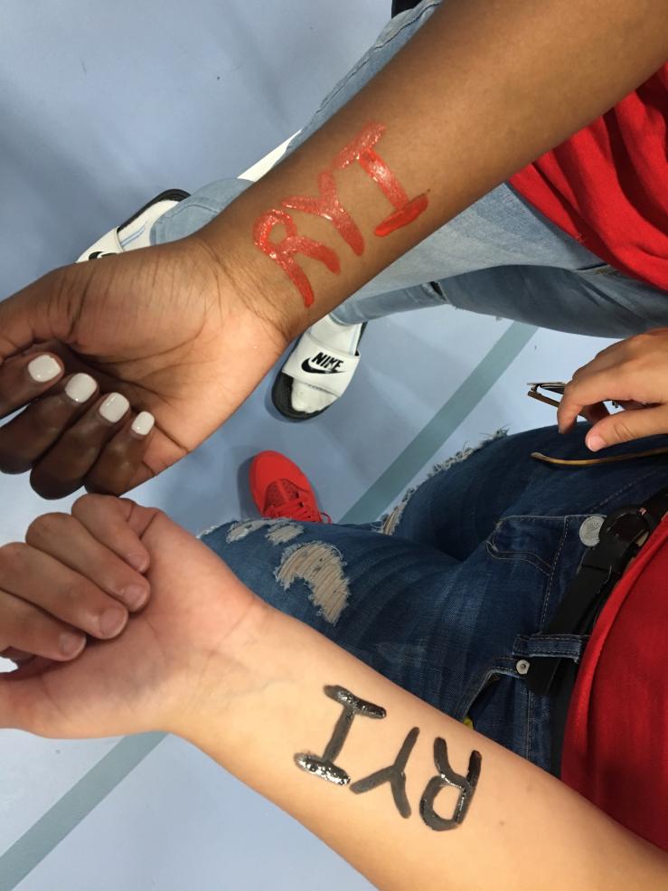 Two students with their arms painted that read: &quot;RYI&quot;