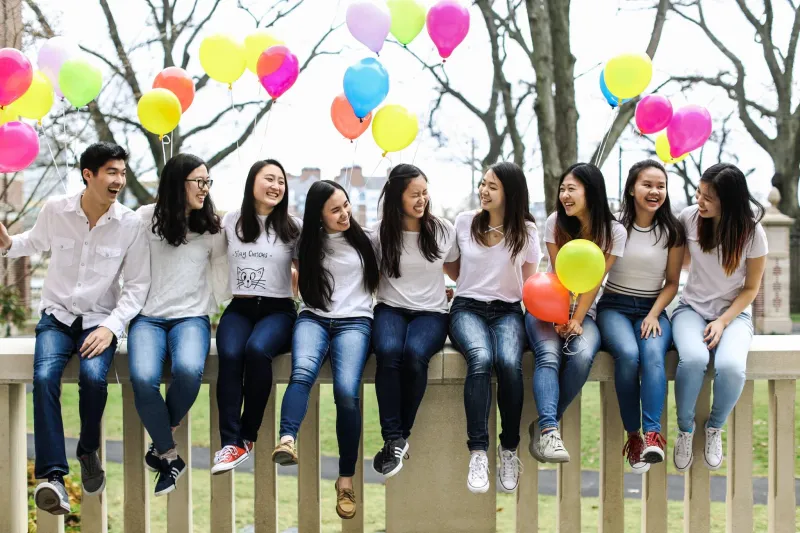 Photograph of members from Asian American Dance Troupe sitting on a fence